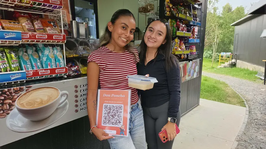 Dos clientas sonrientes con el cartel QR de Don Poncho